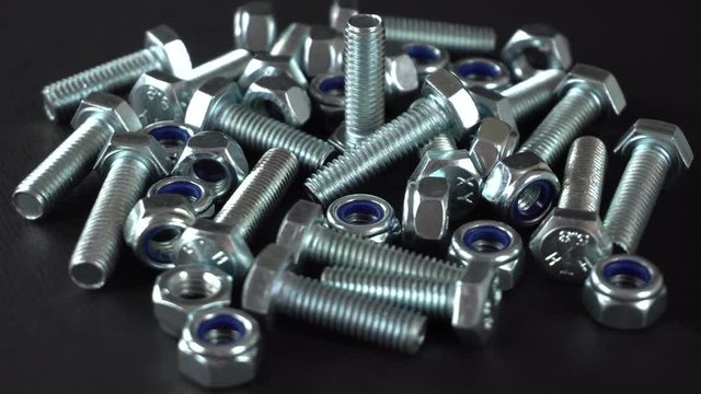Shiny nuts and bolts rotating on a black background. Seamless loopable. Prores 4K.
