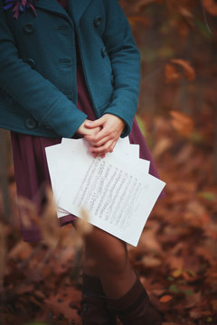 Image of young adult girl in autumn park with paper notes in hand. Copy space for inscription. Woman hold musical notes.