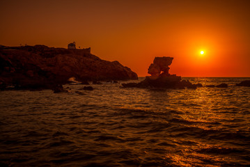 Fels im roten Abendlicht am Meer