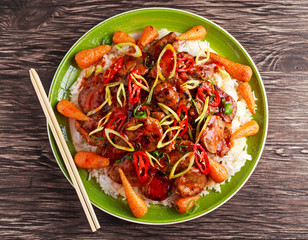 takeawy classic pork on rice with fried in sticky souce carrots, sprinkle of chillie and spring onion.