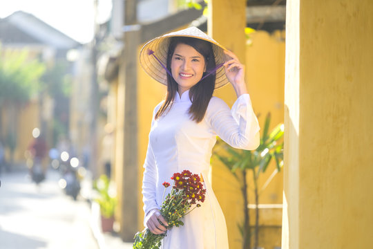 Beautiful woman with Vietnam culture traditional dress, Ao dai is famous traditional costume , vintage style, Hoi an Vietnam, holding the flowers