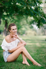 Naklejka premium Beautiful sexy girl in shorts resting in a park on the grass
