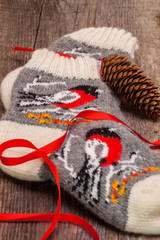 Handmade rustic socks with a winter pattern on the wooden background, pine cone. Christmas holidays concept.