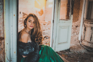 young pretty women with long lush curly blonde hair and thoughtful face in green dress standing...