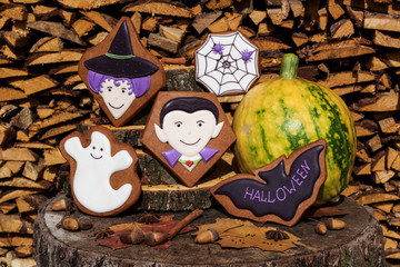 Dracula, witch, ghost, bat, spider in web. Halloween homemade gingerbread cookies and pumpkin on wooden background.