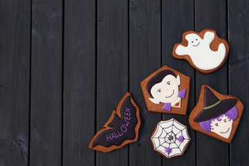 Funny halloween homemade gingerbread cookies on black wooden background. Free place for text.