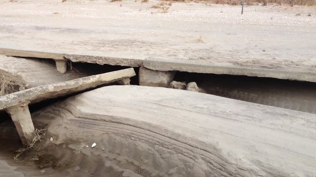 Video clip of Breezy Point Hurricane Sandy wreckage that shows uplift on the underside of cracked  concrete walkway to beach. Video clip pans across cement path and reveals town of Breezy Point, Queen