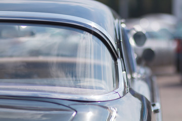Close-up of an old car. Part of the exterior. An American classic. Chrome lining. Glass with reflection.