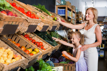 Obraz premium Glad mother with daughter shopping various veggies