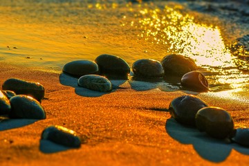 Kamyki na morskim brzegu w ciepłych promieniach zachodzącego słońca