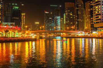 Dubai Marina bridge on night. Dubai Marina skyline illuminated reflects in the bay. Dubai Marina is a modern and futuristic district.