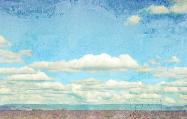 Rural cloudscape with flat road and power lines in foreground and mountain range in background. Faded and textured image with copy space.