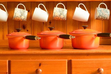 Kitchen dresser with new cooking pans and coffee mugs