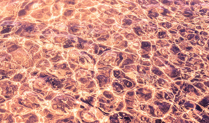 Abstract tectured of stiring clear water reflection with sun lig
