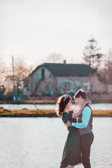 Charming bride, elegant groom on landscapes of mountains and sunset at lake. Gorgeous wedding couple. Man in blue shirt and waistcoat. Woman in  green dress and crown.