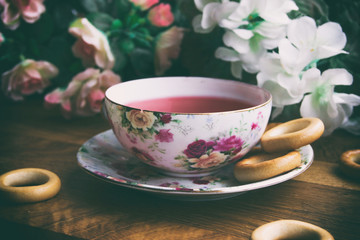 against the background of pink roses and drying tea cup