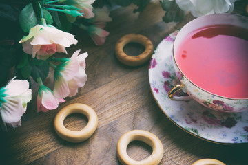 against the background of pink roses and drying tea cup