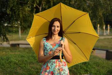 Uśmiechnięta dziewczyna z żółtą parasolką.
