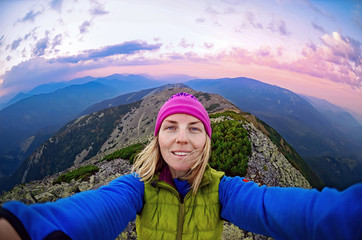 Smiling young woman takes a selfie  on  the  top of   mount Great Sivulja  ,Carpathian ,Ukraine

