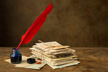 Red quill feather and old letters