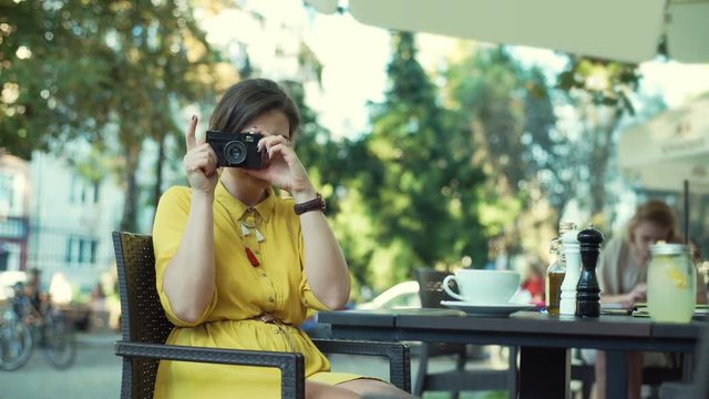 Woman doing photos on old, vintage camera and smiling 
