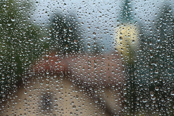 Rain drops on window with house and church in background