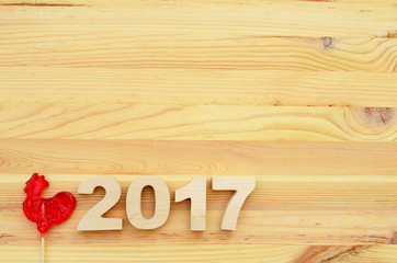 Red rooster, symbol of 2017 on the Chinese calendar. Lollipop in the form of a red rooster on a wooden background