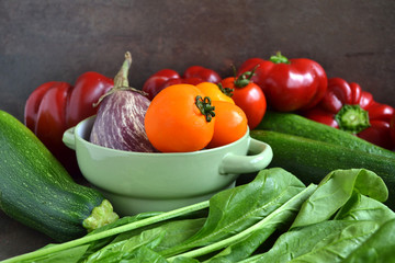A group of fresh vegetables - green spinach, yellow tomatoes,marrow,eggplant, sweet red pepper.