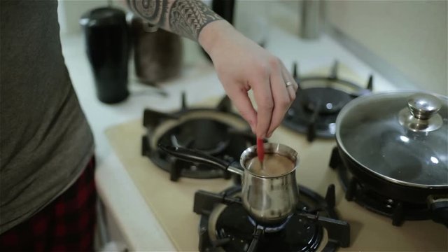 A man stirring coffee with a tablespoon.