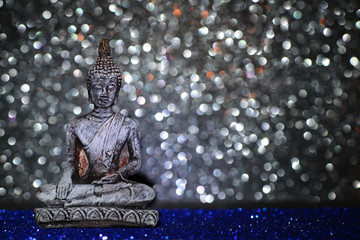 Zen Buddha statue on a bright shiny glitter background with bokeh