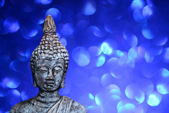 Zen Buddha statue on a bright shiny glitter background with bokeh