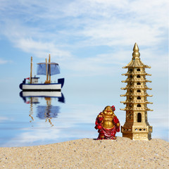 Fototapeta na wymiar Laughing Buddha and seven-storied pagoda in the sand. Symbol of good luck and prosperity in Feng-Shui