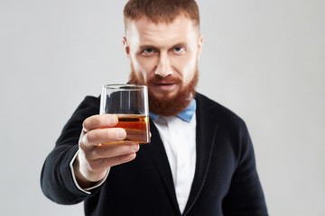 stylish handsome bearded man offers whiskey.Elegant man keeps and holds a glass