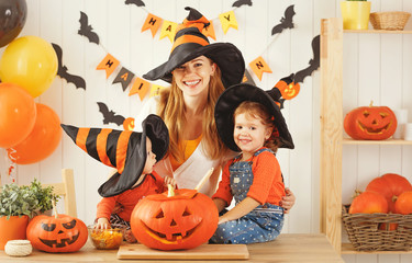 Happy family of mother and children prepare for Halloween pumpki