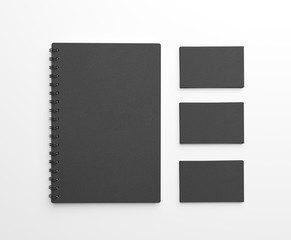 Black paper notebook and stack of business cards over white background. Top view. 3d rendering