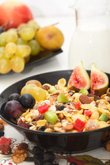 Homemade Muesli with a mix of healthy fruit, nuts and seeds. Fresh grapes, figs and apples in background.