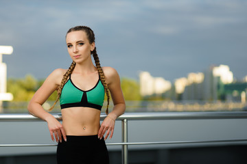Obraz premium Concept: healthy lifestyle, sport. Attractive happy girl fitness trainer do outdoor workout at modern downtown urban area during sunset.