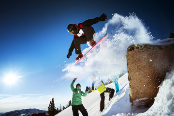 Snowboarder jumps on blue sky backdrop in mountains trick