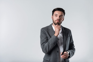 Meditating bearded man standing against white background.