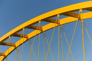 Fotobehang Bruggen Gele brug tegen een staalblauwe lucht met balken, liggers, kolommen en kabels  © mikevanschoonderwalt