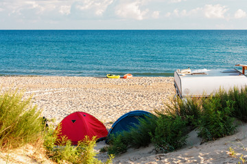 Camping on a sandy sea beach featuring two lone boats