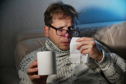 Sick man blowing his nose in the tissue, sick man snotty drinking warm healing tea