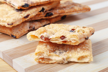 Puff cookies with raisins on a cutting board made of bamboo stripes.