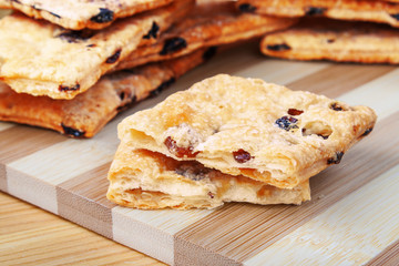 Puff cookies with raisins on a cutting board made of bamboo stripes.