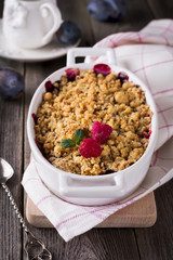 Plum and raspberry crumb on the old wooden background. Rustic style. Selective focus.