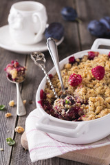 Plum and raspberry crumb on the old wooden background. Rustic style. Selective focus.