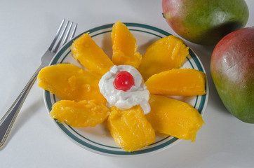 Above view of one plate of sliced mango with yogourt and cherry