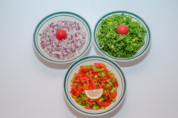 Above view of three bowls filled with chopped onions,peppers and cilantro-parsely