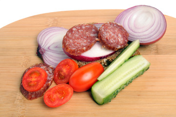 summer sausage , salted cucumber, red cherry tomatoes and sliced red onion Bamboo cutting board , traditional snack while drinking vodka