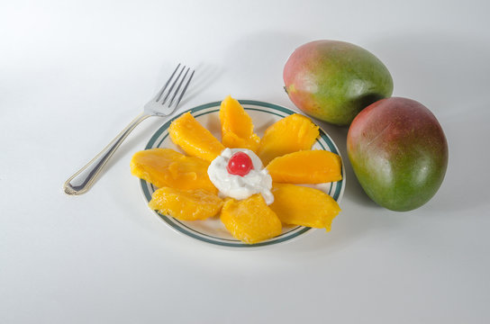 One plate of sliced mango with yogourt and cherry